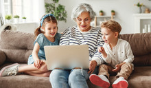 Happy Aged Woman With Grandchildren Using Laptop At Home.
