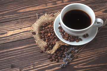 Wall Mural - Cup with black coffee, coffee beans and sprigs of lavender on a wooden tabletop. View from above