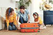© JenkoAtaman - Happy parents with daughter with suitcase setting off for journey.