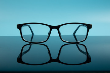 Wall Mural - black frame spectacles glasses with reflection on blue background.