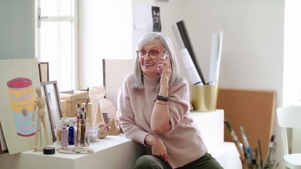 Canvas Print - Senior woman with smartphone making phone call in art class.
