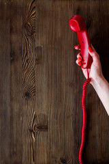 Handset in hand on wooden background top view copy space