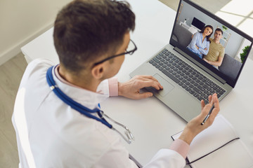 nline doctor talks with a couple patients using a laptop.