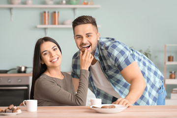 Wall Mural - Beautiful young couple eating chocolate in kitchen