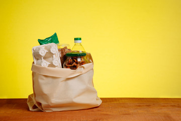 Different Food In Paper Bag on Wooden Table, on Yellow Background. Grocery Shopping Concept