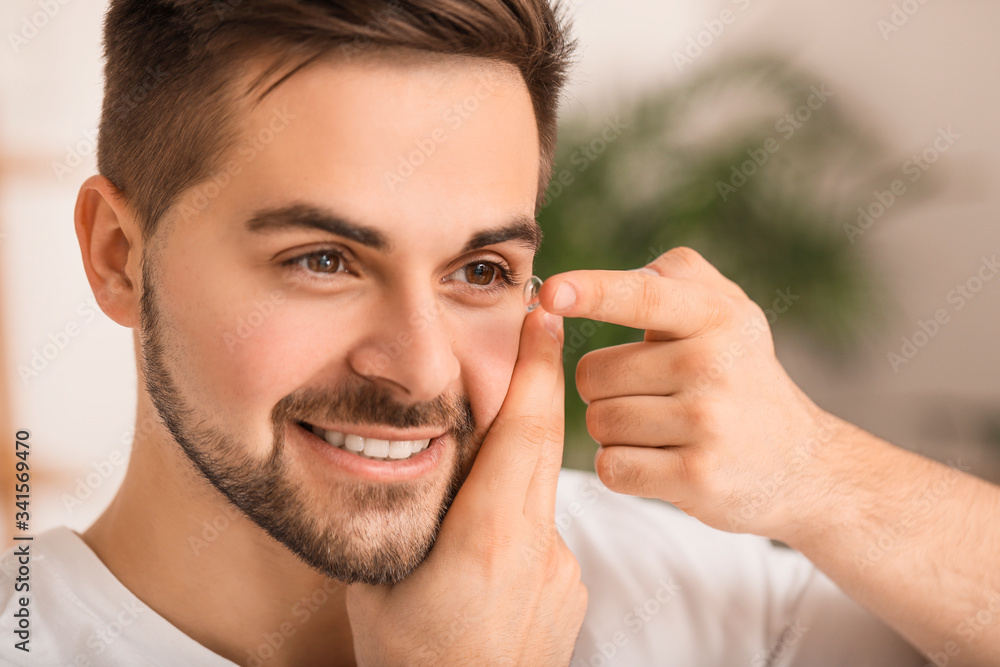 Young man putting in contact lenses at home