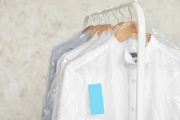 Poster - Rack with clothes after dry-cleaning on light background