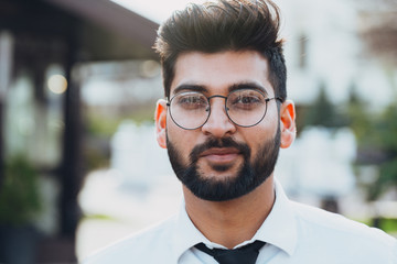 bearded indian man walks down the street.