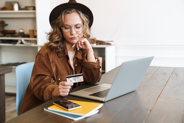 Canvas Print - Image of displeased young woman working with laptop and holding credit