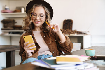 Canvas Print - Image of woman using cellphone while studying with exercise books