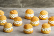 Chou pastry biscuits filled with whipped cream on grey background. Concept: bakery, french dessert. 