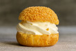 Pastry biscuit filled with whipped cream isolated on grey background. Close up. Concept: bakery, french dessert. 