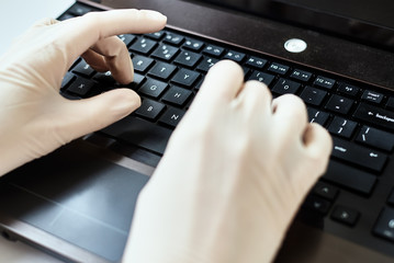 Hands in gloves typing on the laptop keyboard. Virus protection concept