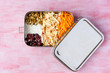 Vegetarian carrot and apple salad in a big stainless steel food container. Plastic free lunch box isolated on pink background. Zero waste, eco friendly. 