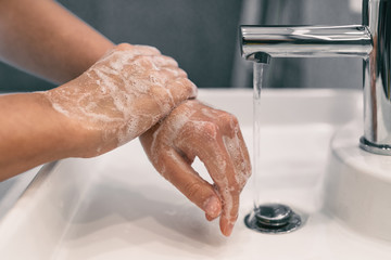 Wall Mural - Hand washing personal hygiene woman washing hands rubbing soap for 20 seconds following steps, cleaning wrists and rinsing under water at home bathroom. COVID-19 infection prevention handwashing.