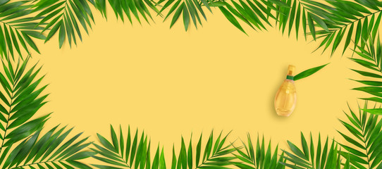 Minimal tropical green palm leaf with perfume in glass bottles  on yellow  paper background.