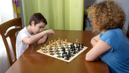 Niño jugando al ajedrez con su mama durante la  cuarentena y el confinamiento en casa por el covid-19