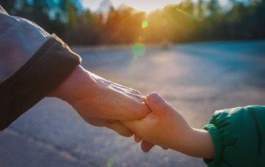 grandmother holding grandchild hand outside, family care