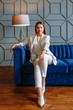 © Alexey Tsibin - A model girl in a business suit on a blue sofa. Clothing demonstration in a showroom.
