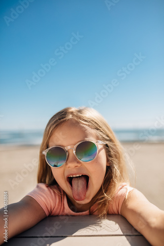 Fotomural Playful girl at the beach sticking out her tongue