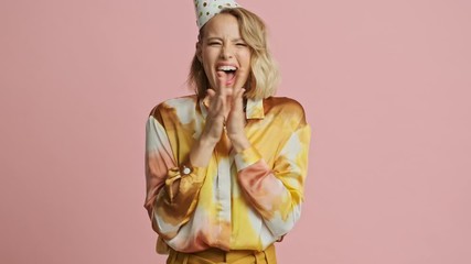 Canvas Print - Pretty blonde woman in colorful elegant costume and party cone becoming surprised and rejoicing after that over pink background