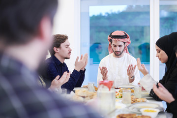 Wall Mural - traditional muslim family praying before iftar dinner