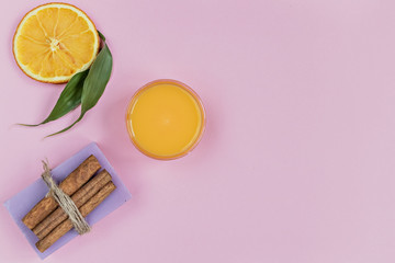 Home spa concept. On a blue background, items accompanying personal care: lavender soap and mango cream for face and body after. For aromatherapy: cinnamon sticks, sliced orange