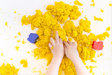 Yellow Magic Sand In A Kids Hands On A White Background Close Up. Early Sensory Education. Preparing For School. Development