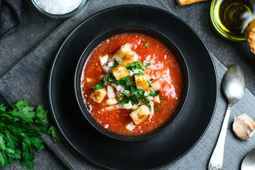 Wall Mural - Traditional spanish cold tomato soup gazpacho in a bowl over black slate, stone or concrete background.Top view with copy space.