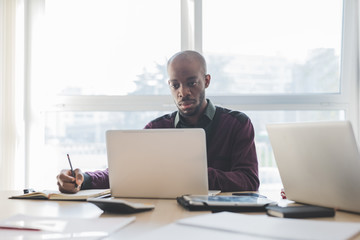 Young adult black ethnicity contemporary businessman indoors using computer writing document