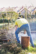 Mężczyzna pracuje w ogrodzie wiosną, przekładając widłami obcięte gałęzie