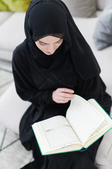 Wall Mural - young muslim woman reading Quran at home