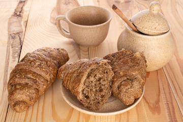 Group of one whole two halves of baked wholegrain croissant for breakfast on wood