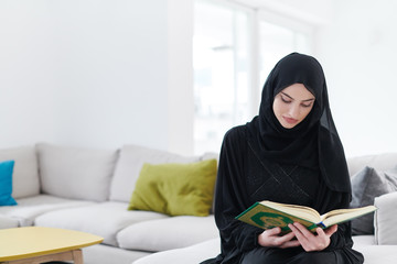 Wall Mural - young muslim woman reading Quran at home