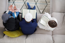 Muslim Family Reading Quran And Praying At Home Top View