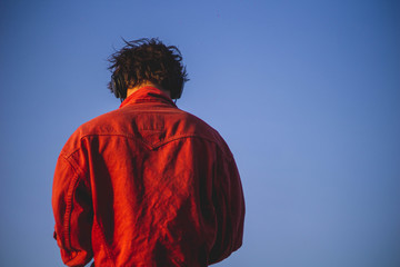 guy in red jacket listening to music over the sea