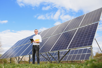 solar panels and blue sky.man standing near solar panels. solar panel produces green, environmentall