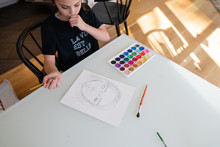 Teenage Girl Drawing A Self Portrait At The Kitchen Table
