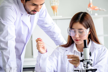 Wall Mural - attractive happiness scientist lab technician assistant analyzing sample in test tube at laboratory.