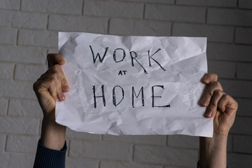 Young caucasian woman is holding in hands a white poster with words written with black pen appealing to self isolation during challenging time COVID-19 pandemic