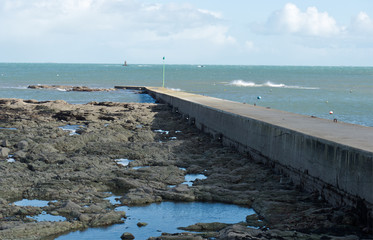 Plage de la ville de Loctudy en Bretagne dans le Finistère vagues puissantes, digue aux formes géométriques, rochers, algues, marée montante et descendante viennent parfaire ce sublime paysage marin