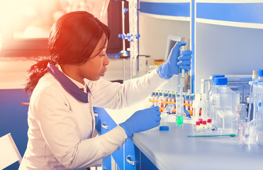 Wall Mural - African scientist or graduate student in lab coat and protective wear performs RT-PCR testing in modern test laboratory. Learning how to use pcr kits to diagnose Covid-19 patients.