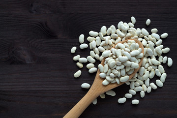 wooden spoon with dried white beans on a wooden table. healthy lifestyle. white beans in spoon on a 