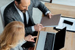 © LIGHTFIELD STUDIOS - Overhead view of businesswoman pointing on laptop near businessman holding documents in office