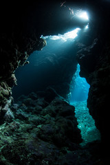 Light seeps into a dark, underwater cavern in the tropical Pacific Ocean. Caves and caverns riddle coral reefs and limestone islands.