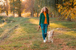 © trofalena - Golden retriever dog with a curly woman walking outdoors on sunny day. Training the dog in the park. love and care for the pet.