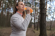 © Evgeniy Agarkov - Sporty woman drinking orange smoothie at sunny day in the park