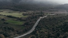 Aerial - Group Of Motorcyclists Driving On A Lonely Mountain Road On A Foggy Day