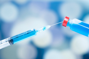 The picture of blue vaccine tube and syringe are on the blur background