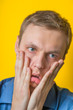 © aeroking - Young businessman in a blue shirt despair with both hands covering the face, showing a sign of depression on a yellow background.